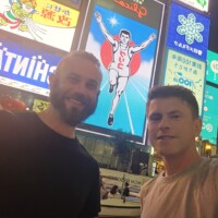 dwóch naukowców na tle wielkich świecących banerów w mieście Osaka po zmierzchu